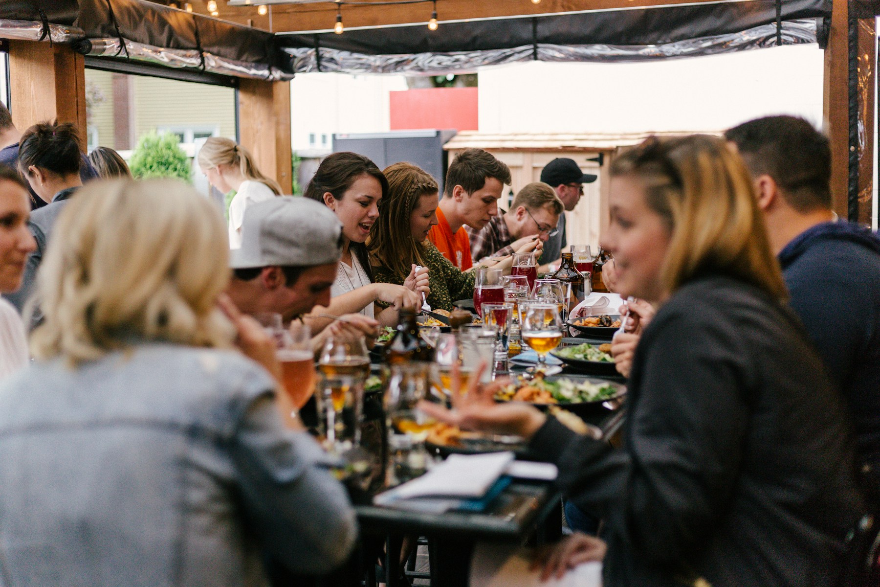 Menschen sitzen an einem langen Tisch, essen und sprechen miteinander